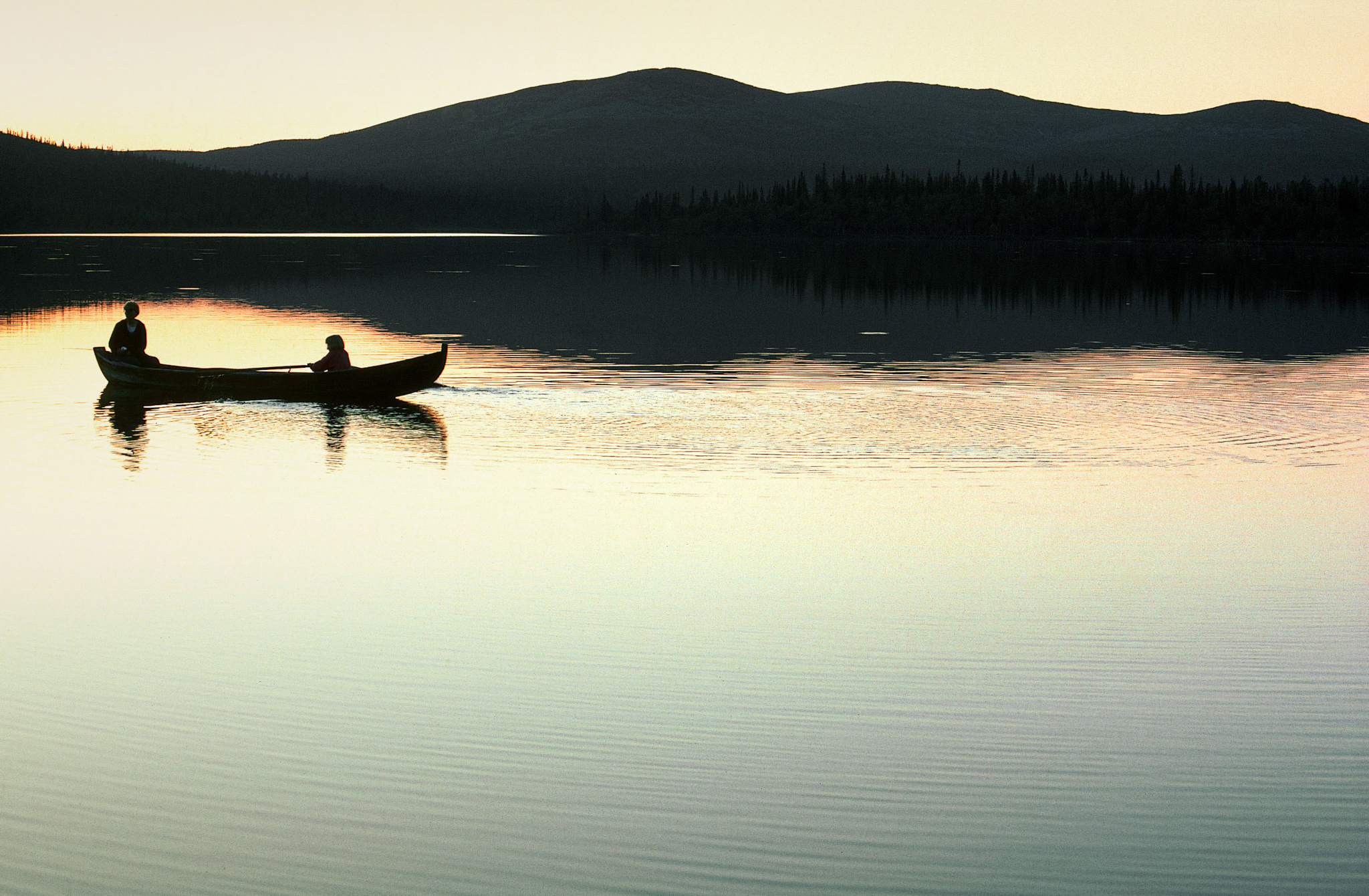 two people paddling in kanu on lake in evening
