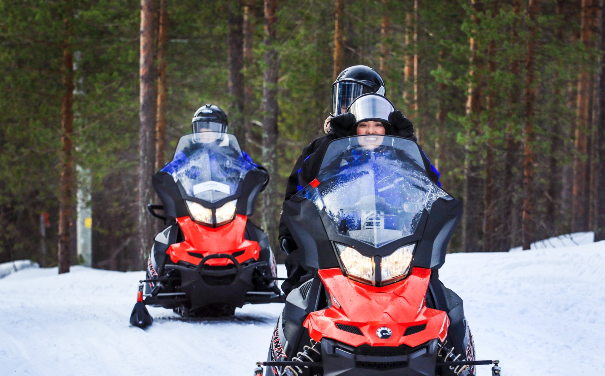 people sitting on snowmobiles