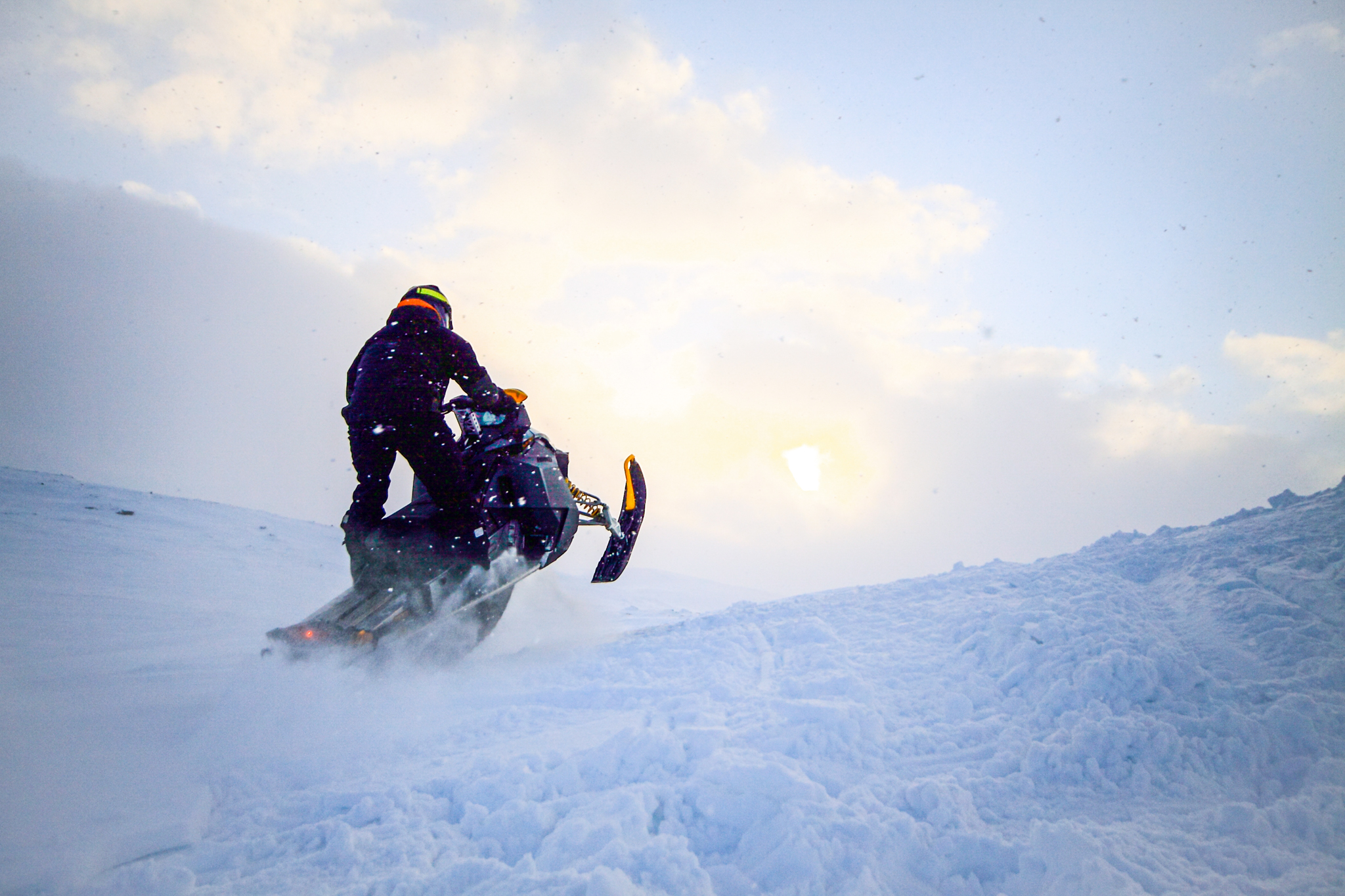 person driving a snowmobile on a hill