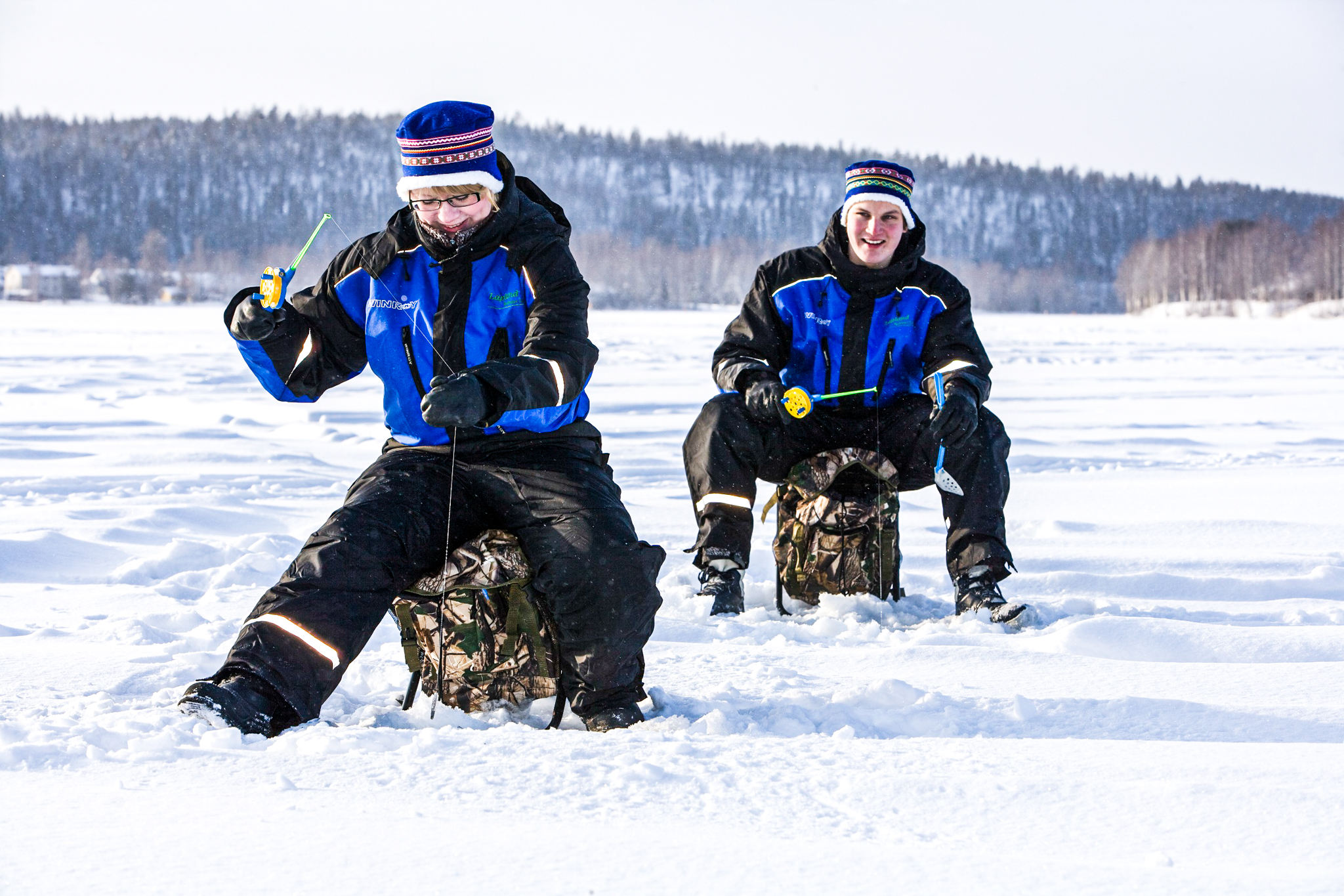 two people during ice fishing on frozen lake